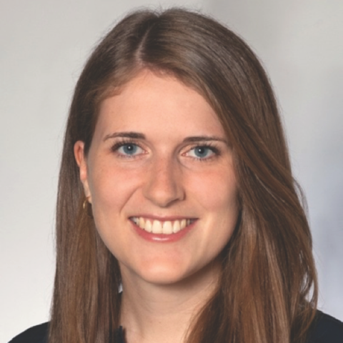 Woman with brown hair smiling at camera, wearing black shirt.